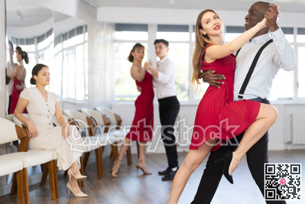 African American and woman in red engrossed in passionate tango during dance class