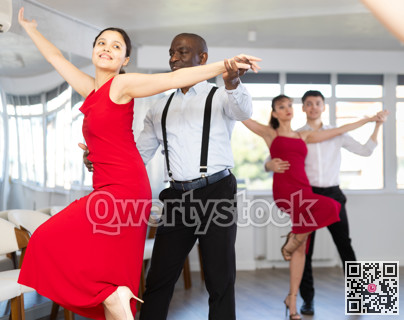 Black man enjoying impassioned merengue with woman in red in studio