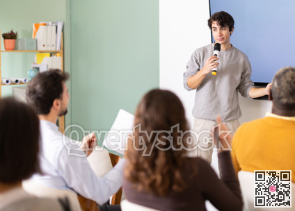 Young man teacher gives lecture to group in lecture hall