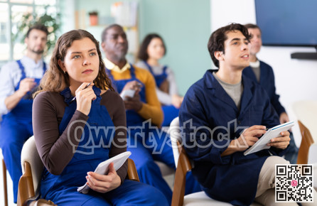 During lecture meeting, group of worker listen to teacher and write down summary