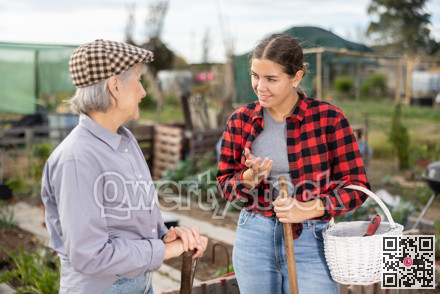 Two female gardeners talking near wooden fence in garden