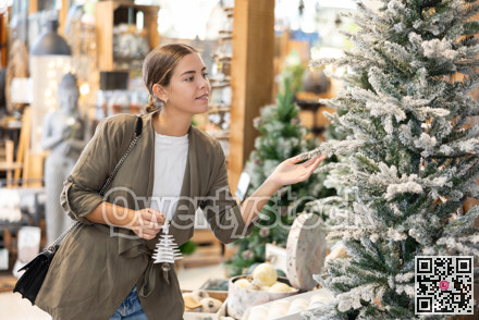 Girl buyer considers New Year and Christmas decorations ornaments for Christmas tree