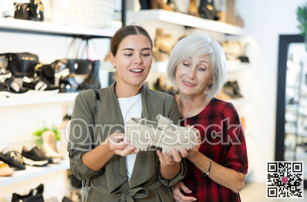 Elderly mother with young daughter view moccasins in footwear store
