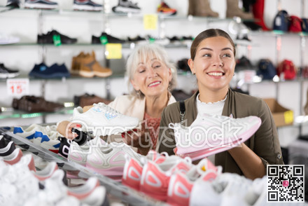 Elderly woman and young woman choosing sneakers in shoe store