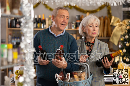 Mature husband and wife choosing wine and whiskey for Christmas celebration at supermarket