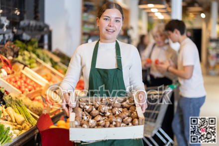 Young woman seller with box of dried mushrooms