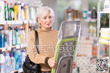 Elderly woman buys convenient lightweight ironing board at hardware store