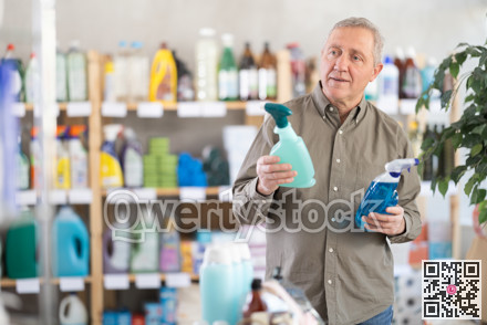 Elderly man choosing cleaning spray in supermarket