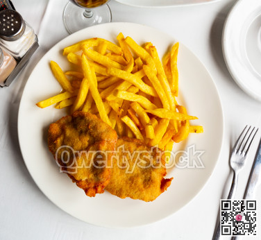 Appetizing breaded pork steak baked in oven with golden french fries