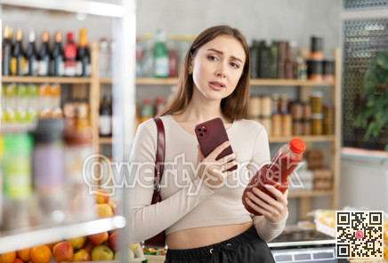 Young woman scanning qr code of tomato juice