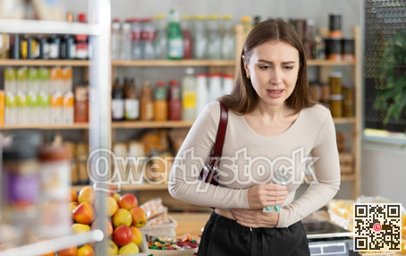 Young woman with stomach pain pills in grocery store