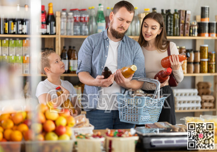 Young family with little son choosing natural juice in supermarket