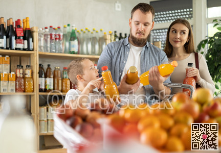 Young family with little son choosing natural juice in supermarket