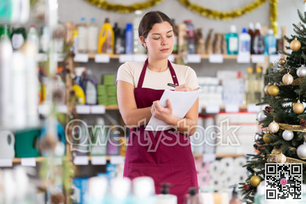 Young woman restocking using paper in store with New Year decoration