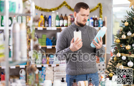 Young man in choosing shampoo in festively decorated hygiene store