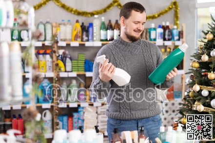 On New Year Eve, man choose and buy liquid washing powder and tile cleaner spray