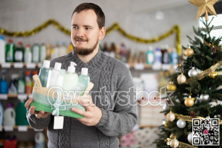 Interested nice bearded man choosing gifts for New Year in household department of supermarket