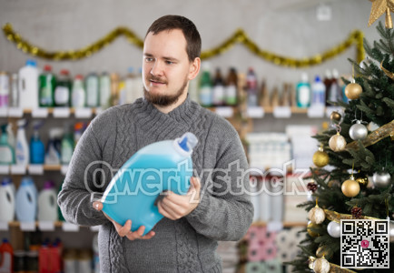 Man choosing detergent while shopping in Christmas decorated store