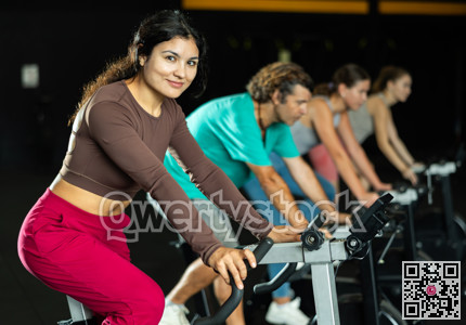 Positive Latina girl doing spin bike exercises in well-equipped gym