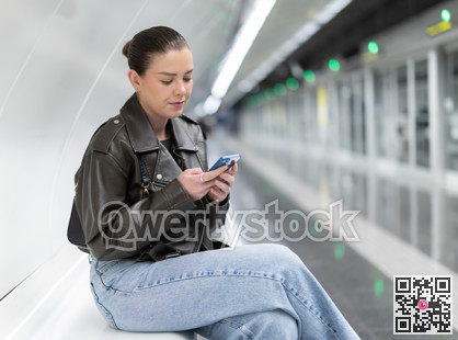 Young woman with phone sitting at metro station