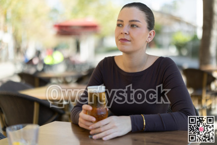 Woman drinking beer while sitting at table on cafe terrace