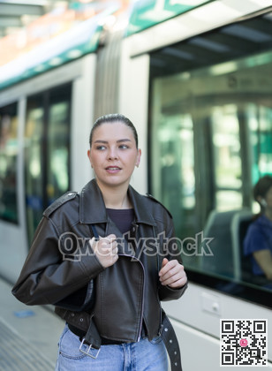 Young woman waiting for tram at public transport stop