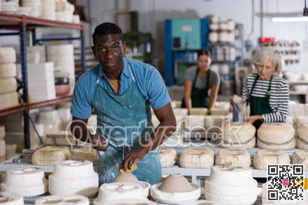 African american man prepares pottery with foam sponge - removes roughness and unevenness