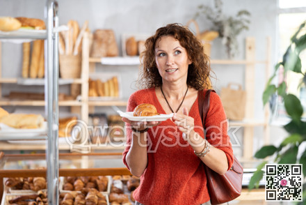European woman customer holding disposable plate with burger in bakery