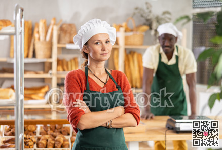 Confident female baker with arms crossed in bakery