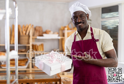 African American man entrepreneur owner of bakery holds out paper bag with pastries in hand