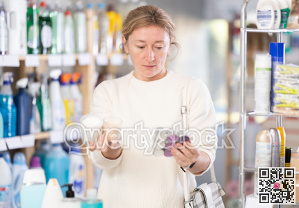 Female shopper chooses scented candles in supermarket for romantic evening