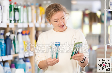 Female shopper chooses toothbrush and toothpaste in supermarket