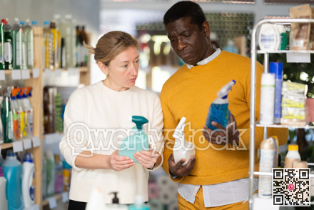 Before buying in household shop, African male customer with European wife choose glass cleaner spray