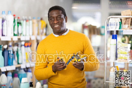 African man in store inspects set of hand tools. Buyer selects necessary items for minor repairs