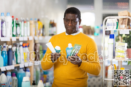 African man decided to buy dental care kit, looking for something in window