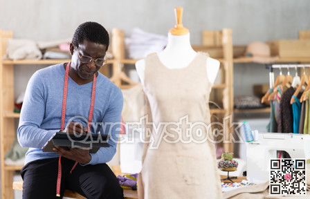 Male dressmaker working on digital sketch of dress in workshop