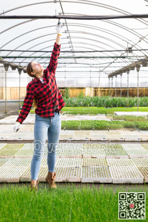 Hardworking young woman farmer opens a tap for watering