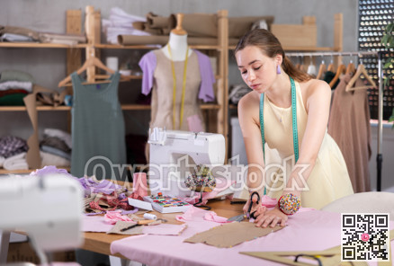 Woman seamstress cutting fabric in sewing workshop