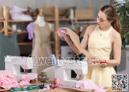 Young woman seamstress with pattern in sewing workshop
