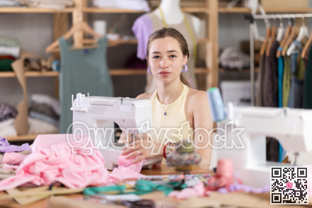 Seamstress working on modern sewing machine in sewing workshop