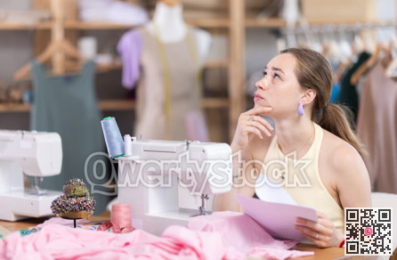 Upset young woman seamstress with documents in workshop