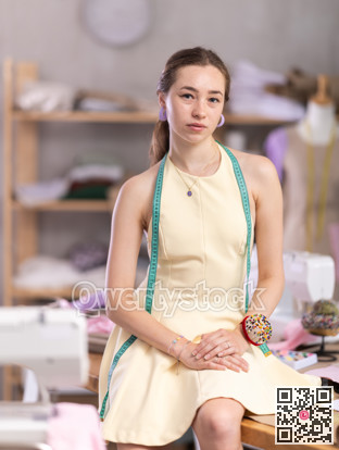 Portrait of positive girl tailor in sewing workshop