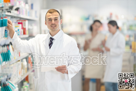 Positive male pharmacist in medical uniform posing while working in pharmacy