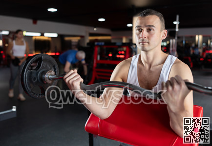 Young man training with barbell in gym