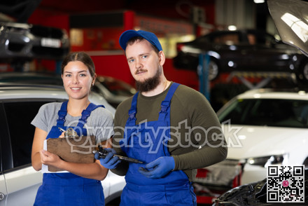 Guy and woman mechanics posing in car service