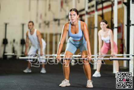 Athletic girl doing squats with barbell in gym