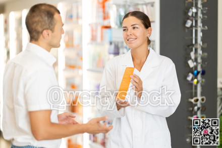 Female pharmacist consulting young guy about medicament in box