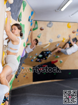 Young woman practicing rock climbing on climbing wall