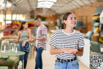 Girl exploring with interest furniture and garden supplies at store