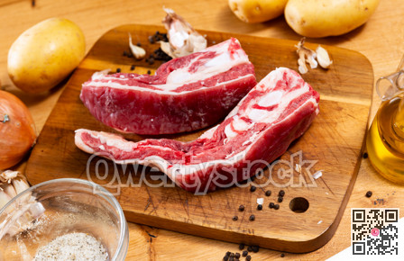 Raw beef ribs on board, potato tubers and whole onions